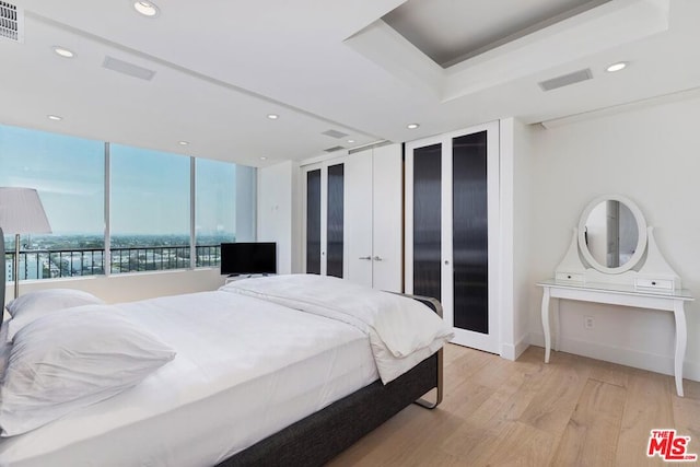 bedroom with a raised ceiling and light wood-type flooring