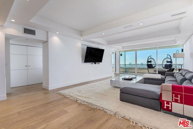 living room featuring light wood-type flooring, a wall of windows, and a raised ceiling