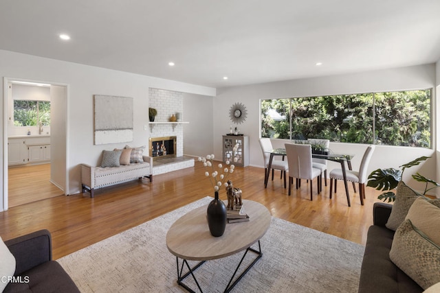 living room with brick wall, light hardwood / wood-style flooring, and a fireplace