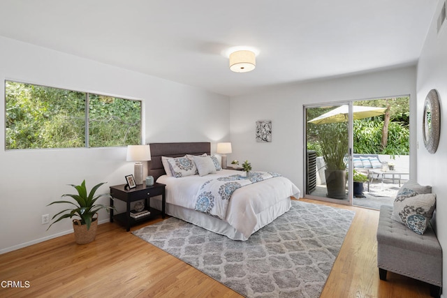 bedroom with multiple windows, hardwood / wood-style flooring, and access to outside