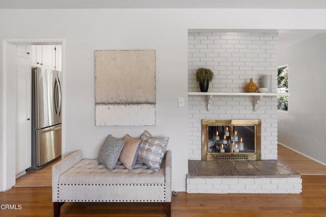 living room with brick wall, a fireplace, and wood-type flooring