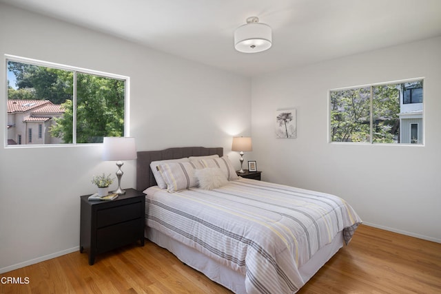 bedroom with multiple windows and light wood-type flooring