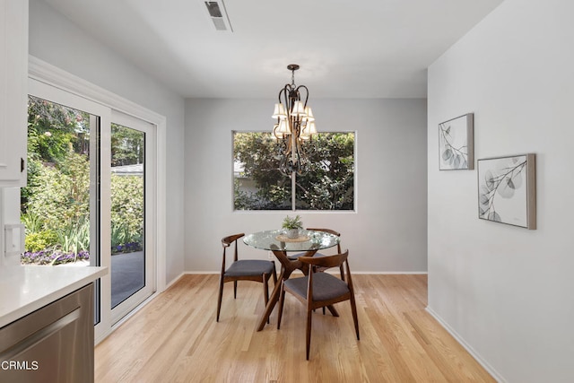 dining room with light hardwood / wood-style flooring and an inviting chandelier