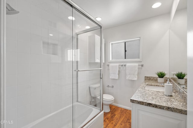 full bathroom with shower / bath combination with glass door, vanity, wood-type flooring, and toilet