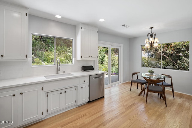 kitchen featuring light hardwood / wood-style flooring, dishwasher, backsplash, decorative light fixtures, and sink