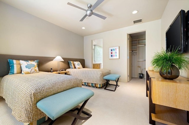 carpeted bedroom featuring a walk in closet, a closet, and ceiling fan