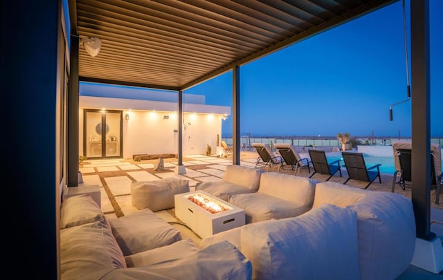 patio terrace at dusk with a swimming pool and an outdoor living space with a fire pit