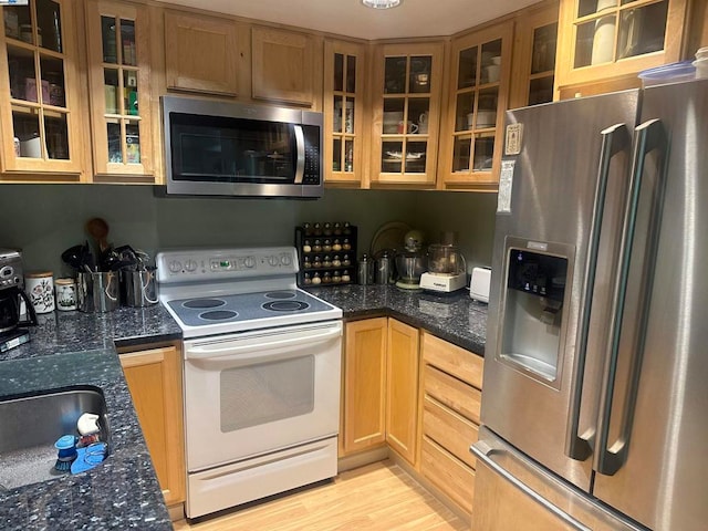 kitchen featuring dark stone countertops, stainless steel appliances, and light hardwood / wood-style floors