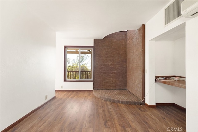 spare room featuring dark wood-type flooring and a wall mounted AC