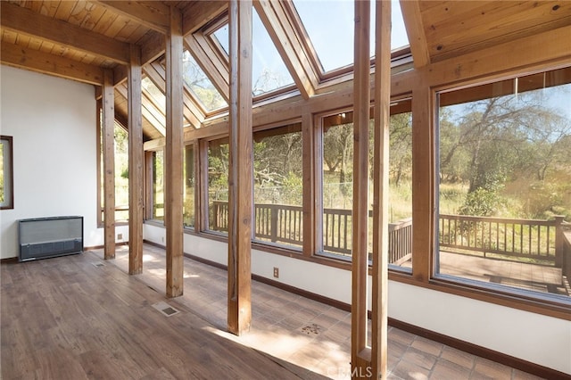 unfurnished sunroom with heating unit, lofted ceiling with skylight, plenty of natural light, and wood ceiling