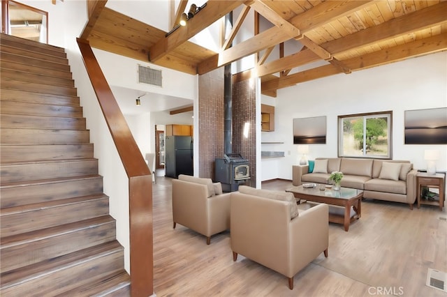 living room featuring beam ceiling, a wood stove, high vaulted ceiling, and hardwood / wood-style flooring