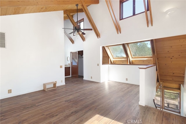 unfurnished living room with a skylight, ceiling fan, dark wood-type flooring, beam ceiling, and high vaulted ceiling