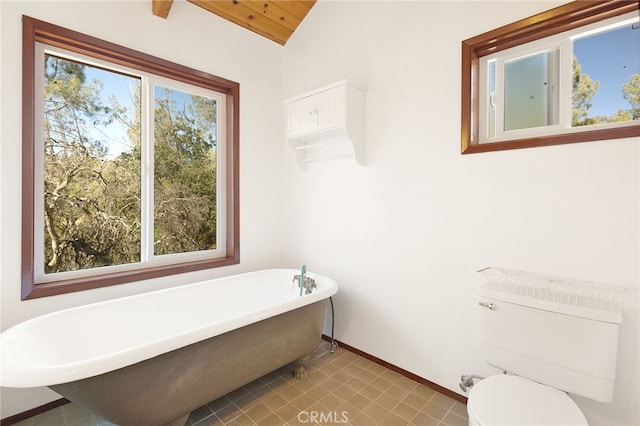 bathroom featuring a healthy amount of sunlight, toilet, a tub to relax in, and vaulted ceiling