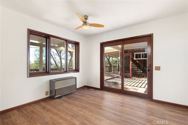 unfurnished room featuring hardwood / wood-style flooring, ceiling fan, and radiator heating unit