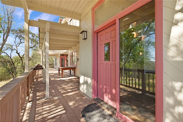 doorway to property featuring covered porch and a wooden deck