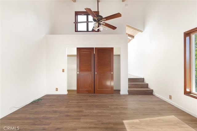 interior space featuring wood-type flooring, a towering ceiling, ceiling fan, and a healthy amount of sunlight