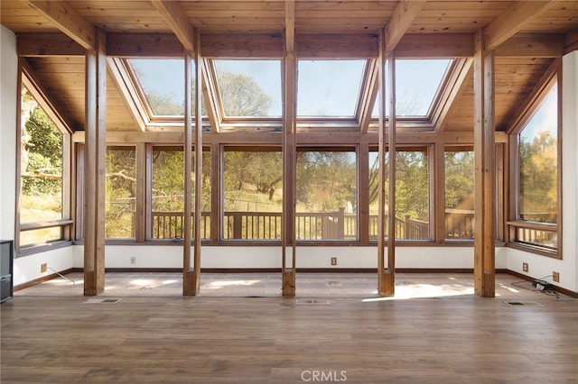 unfurnished sunroom with beam ceiling, a skylight, and wood ceiling