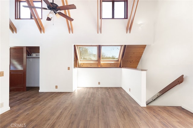 unfurnished living room featuring ceiling fan, dark hardwood / wood-style flooring, and lofted ceiling with skylight