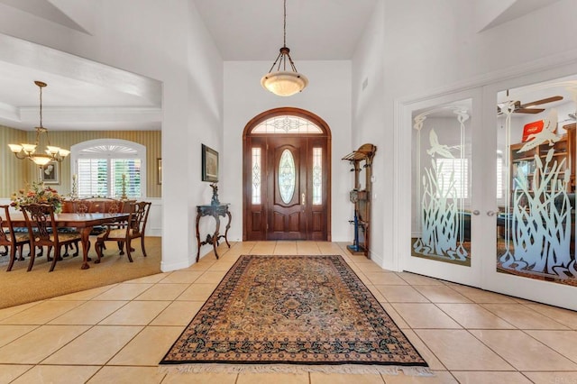 tiled entryway with ceiling fan with notable chandelier and french doors