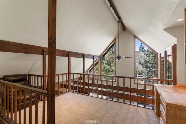 hall featuring lofted ceiling with beams, light colored carpet, and rail lighting