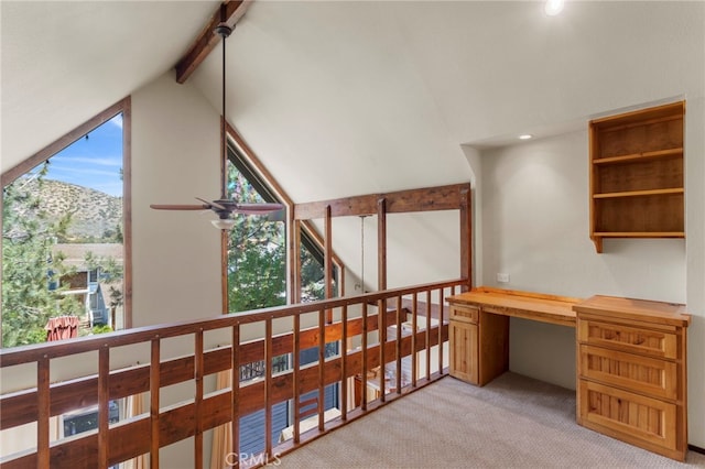 carpeted office space with a mountain view, built in desk, ceiling fan, and lofted ceiling with beams