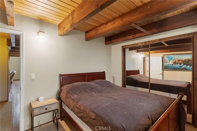 carpeted bedroom with beamed ceiling and wood ceiling