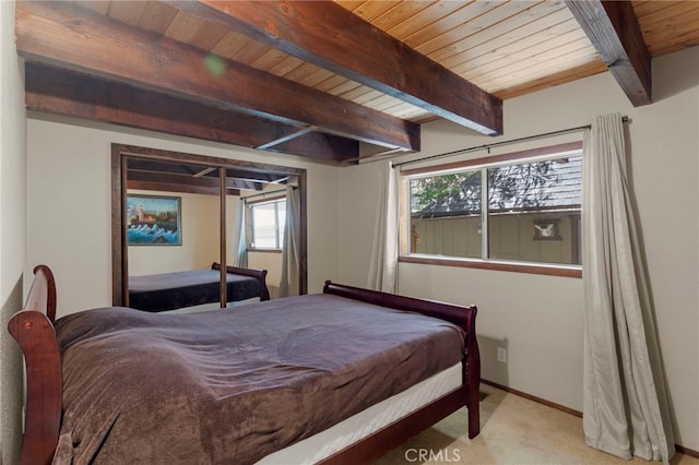 bedroom featuring beamed ceiling, light carpet, and wood ceiling