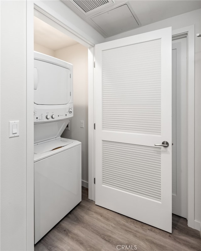 laundry area with stacked washing maching and dryer and hardwood / wood-style flooring