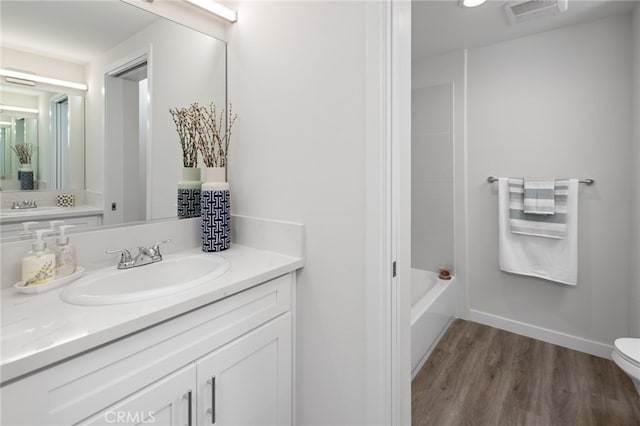 bathroom with wood-type flooring, vanity with extensive cabinet space, and toilet