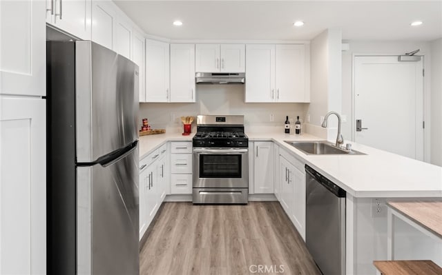 kitchen featuring kitchen peninsula, light wood-type flooring, sink, white cabinetry, and appliances with stainless steel finishes