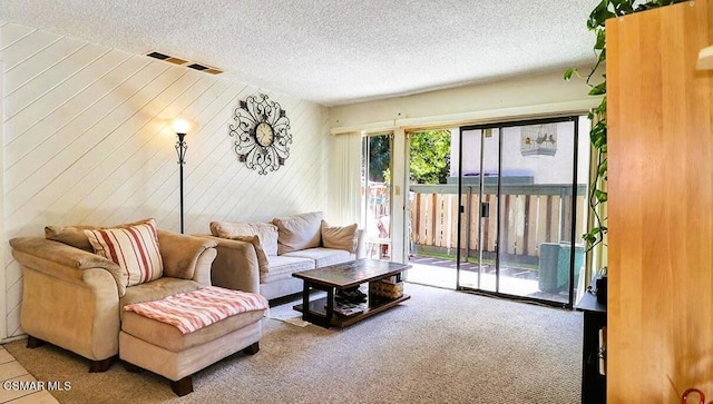 carpeted living room featuring a textured ceiling and wooden walls