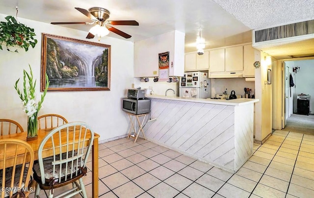 kitchen featuring ceiling fan, light tile patterned floors, kitchen peninsula, white fridge, and white cabinets