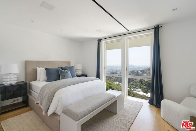 bedroom with light hardwood / wood-style flooring and a wall of windows