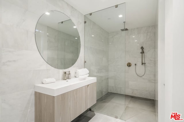 bathroom with vanity, a tile shower, and tile walls