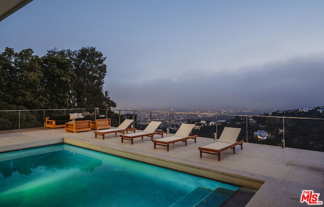 pool at dusk featuring outdoor lounge area