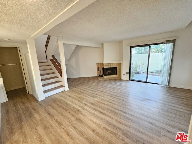 unfurnished living room featuring a fireplace, a textured ceiling, and hardwood / wood-style floors