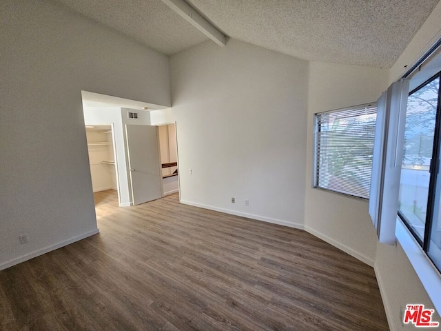 unfurnished room with high vaulted ceiling, dark wood-type flooring, beamed ceiling, and a textured ceiling