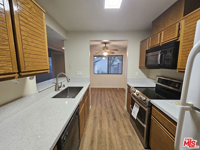 kitchen featuring light hardwood / wood-style floors, ceiling fan, black appliances, light stone countertops, and sink