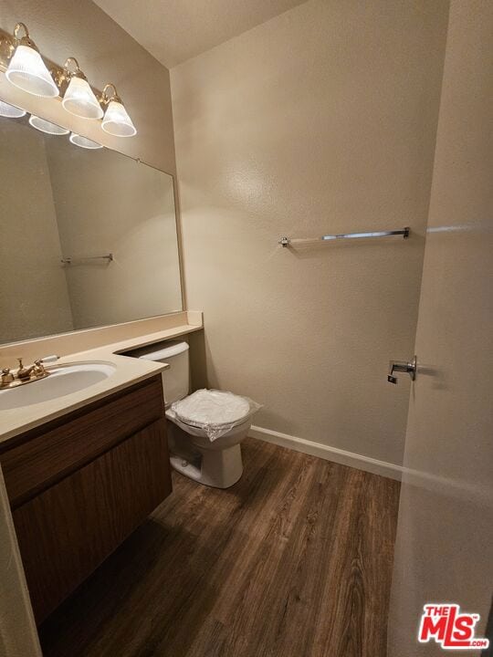 bathroom with wood-type flooring, vanity, and toilet