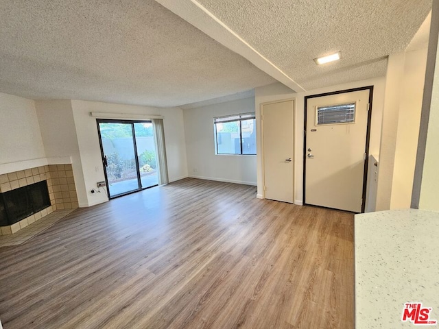 unfurnished living room with wood-type flooring, a textured ceiling, and a fireplace