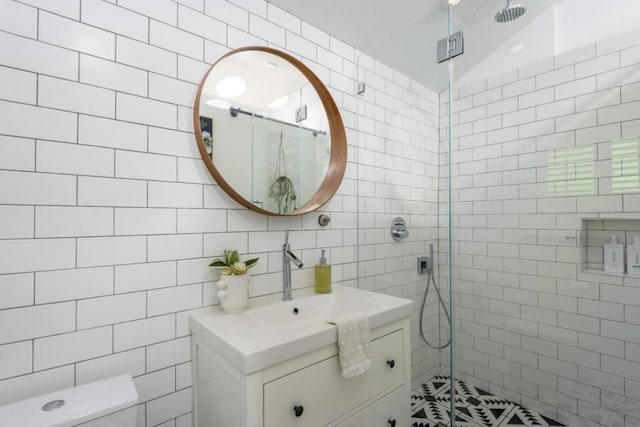 bathroom with tile walls, toilet, vanity, and an enclosed shower