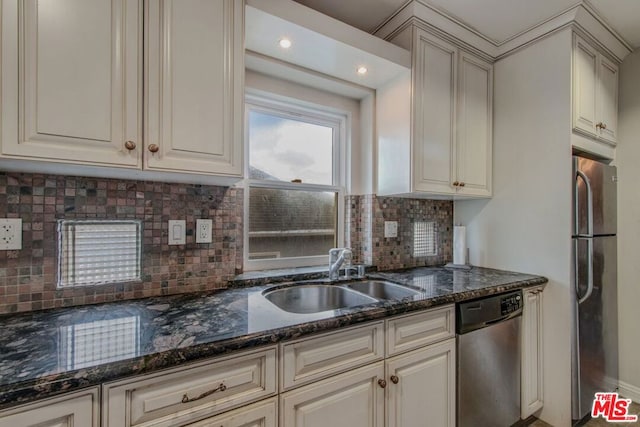 kitchen with appliances with stainless steel finishes, tasteful backsplash, dark stone counters, and sink