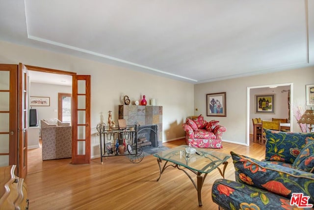 living room with wood-type flooring, french doors, and a tiled fireplace