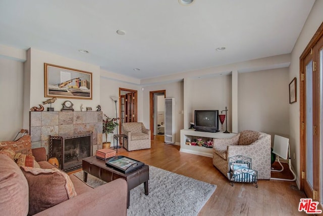 living room with a tile fireplace and light hardwood / wood-style floors