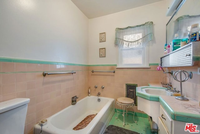 bathroom with tile patterned flooring, a washtub, tile walls, and vanity