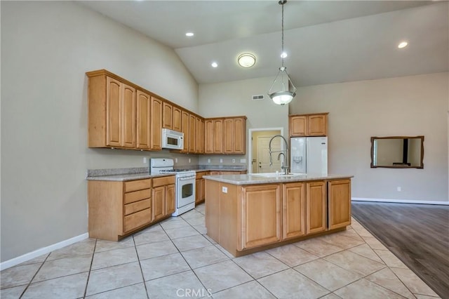 kitchen featuring white appliances, vaulted ceiling, a kitchen island with sink, pendant lighting, and light hardwood / wood-style floors