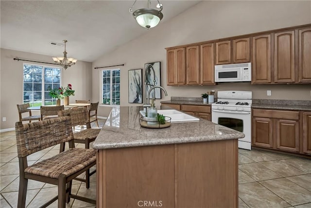 kitchen featuring white appliances, decorative light fixtures, sink, and a kitchen island