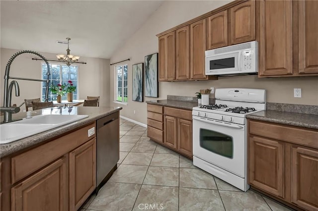 kitchen featuring vaulted ceiling, sink, hanging light fixtures, light tile patterned floors, and white appliances