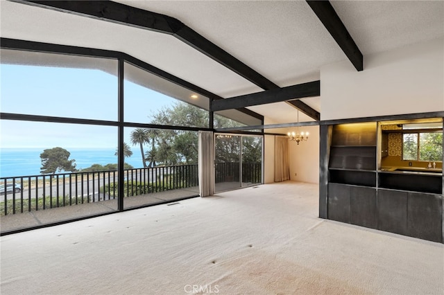 interior space featuring a wealth of natural light, beamed ceiling, a notable chandelier, a water view, and carpet