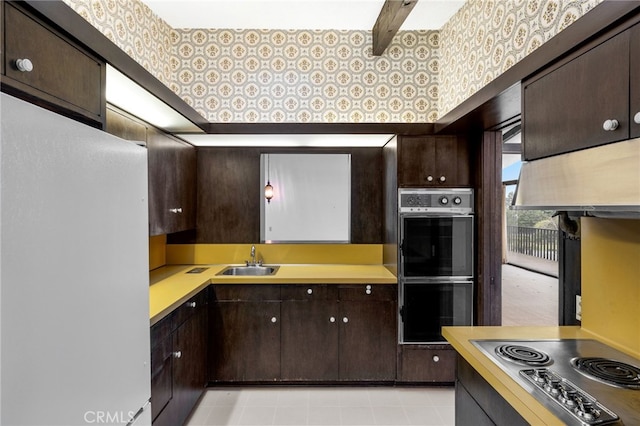 kitchen with stainless steel gas stovetop, dark brown cabinets, sink, and double oven